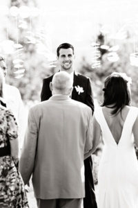 Groom smiling at bride walking down aisle